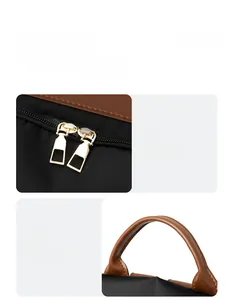 Detail view of the sleek dual golden zippers and comfortable leather handle on the backpack
