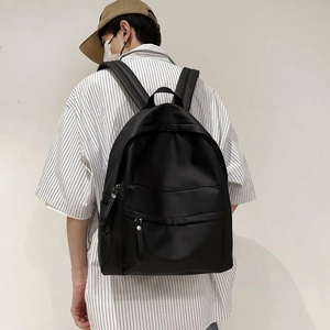 Close-up of minimalist black backpack with wide padded straps and waterproof fabric detail
