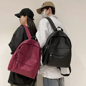 Burgundy and black minimalist nylon backpacks shown with front zipper pockets