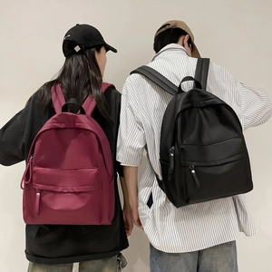 Rear view of model wearing burgundy and black large capacity nylon school backpacks