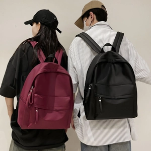 Rear view of minimalist large capacity backpacks in burgundy and black on model