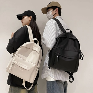 Detail view of minimalist nylon backpacks in cream and black on male and female models