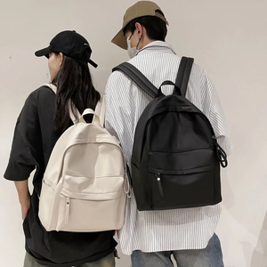 Close-up of minimalist nylon backpacks in cream and black featuring large main compartments