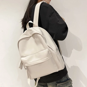 Side view of cream white minimalist backpack with front zipper pocket on model