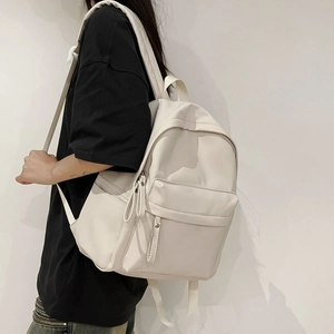 Detail view of large cream white backpack showing smooth texture and side storage pocket