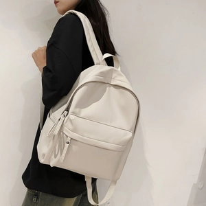 Side view of a white minimalist backpack worn by a model against a clean white wall