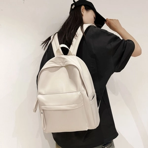 Close-up of beige leather backpack with spacious front zipper pocket and side pocket