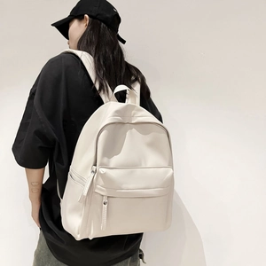 Detail view of large cream white backpack with smooth texture and wide shoulder straps