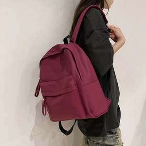 Detail view of burgundy nylon backpack featuring large main compartment and front pocket
