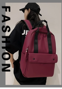 Detail view of a large burgundy backpack with a front flap pocket and sturdy black handle