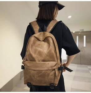 Brown vintage style backpack in matte synthetic leather on model's back in a hallway