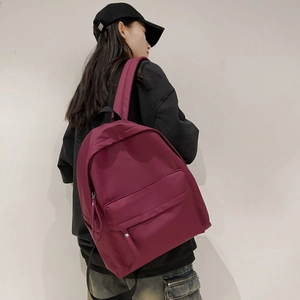 Detail view of burgundy waterproof backpack with multiple compartments on a model