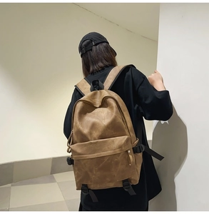 Back view of a street style brown leather backpack with multiple compartments on a model