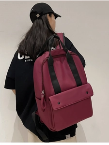 Detailed view of burgundy waterproof backpack with black straps and double snap pocket