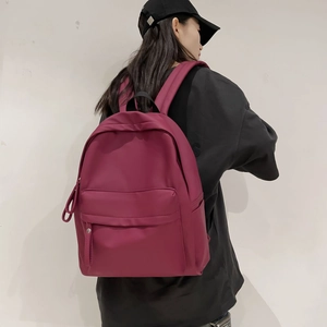 Detail view of burgundy waterproof backpack showing side pockets and padded straps on model