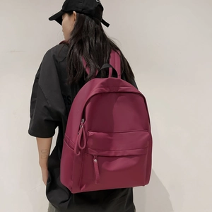 Detail of burgundy waterproof nylon backpack with dual zippers and large capacity design