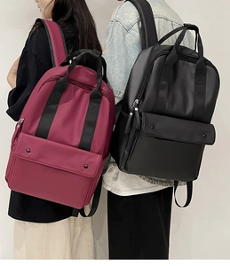 Dual view of burgundy and black large capacity nylon backpacks with front buckle pockets