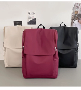 Detailed view of casual backpacks in cream, wine red, and black with large flap design