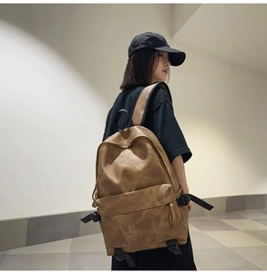 Detailed side view of the retro brown leather backpack worn by a model in a modern hall