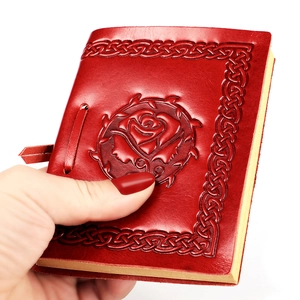 Detail of red embossed leather notebook featuring rose patterns and rustic tie closure