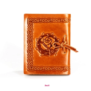 Detail of vintage brown leather notebook featuring embossed rose and Celtic knot border