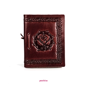 Macro view of burgundy leather notebook with rose embossing and Celtic knot border