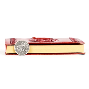 Vintage red embossed leather notebook with rose carving shown next to a coin for scale