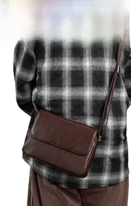 Detail of dark brown pebble leather crossbody bag with adjustable strap worn by model