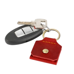 Détail de l'étui à clés en cuir rouge avec bouton pression doré et coutures jaunes contrastées
