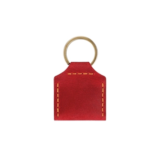 Détail macro du porte-clés en cuir rouge avec coutures jaunes et anneau en laiton