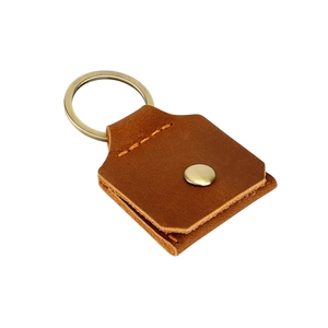 Détail d'un porte-clés en cuir marron avec anneau en cuivre et surpiqûres précises