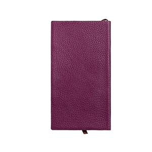Gros plan sur la texture du cuir grainé violet foncé de la couverture de carnet