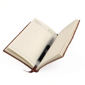 Détail macro du carnet B5 en cuir montrant les pages lignées, la recharge et le ruban