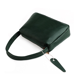 Close-up of dark green lychee textured leather underarm bag with heart charm