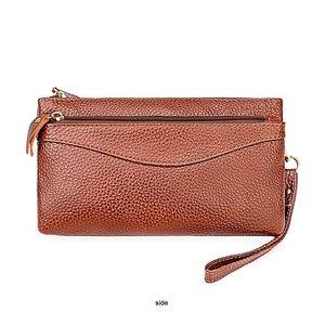 Macro detail of brown pebble grain leather surface and golden zipper on wristlet bag