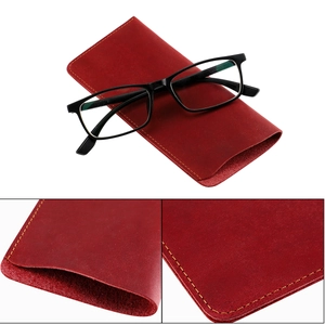 Detail view of red leather glasses case with yellow stitching and classic black eyewear