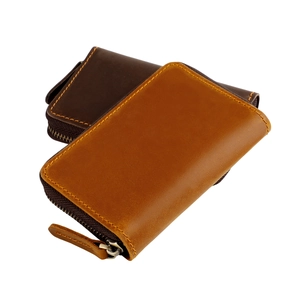 Detail of vintage leather key pouch with heavy yellow stitching and metal zipper closure
