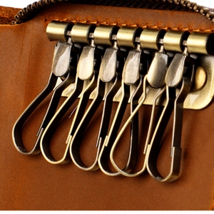Close-up of six antique bronze metal hooks inside a vintage brown leather key wallet