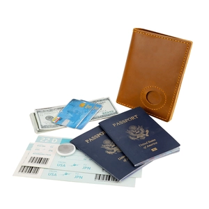 Close-up of leather passport holder with AirTag slot and travel essentials on white background