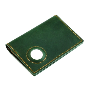 Detail of dark green leather passport cover with contrast stitching and Airtag slot