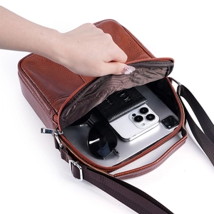 Brown litchi grain leather crossbody bag for men showing spacious interior storage