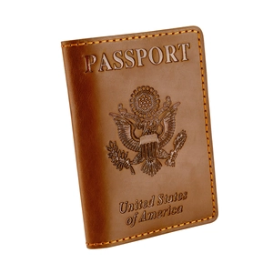 Macro detail of brown leather US passport cover with embossed eagle seal and yellow stitching