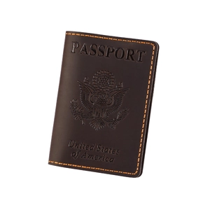 Detail of dark brown leather passport cover with embossed US eagle emblem and orange stitching