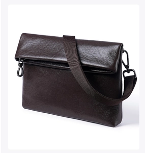 Vue détaillée de la texture du cuir marron foncé et de la boucle en métal du sac pour homme