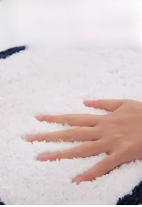 Close-up of soft white plush bath mat with deep blue border showing rapid suction texture