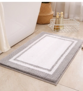 Close-up of grey and white flocked absorbent bathroom mat beside a white bathtub