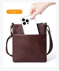Close-up of front pocket on brown leather crossbody bag showing smartphone storage capacity