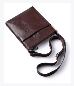 Detail of dark brown leather messenger bag with metal zipper and adjustable strap