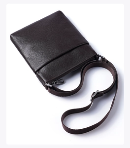 Detailed close-up of dark brown men's crossbody bag with lychee grain leather texture