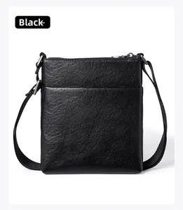 Close-up of black lychee grain leather crossbody bag with zipper and front pocket detail